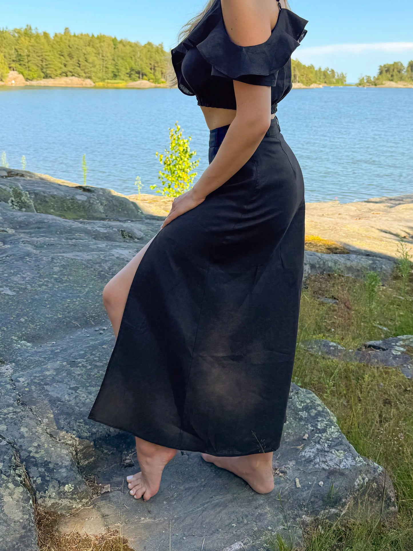 model wear best high waisted linen skirts in Australia. Made from 100% pure French linen, our black skirts feature a stylish thigh slit for breathable comfort and effortless elegance.